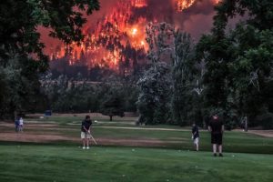 Image of golfers in Washington with raging fires in background.